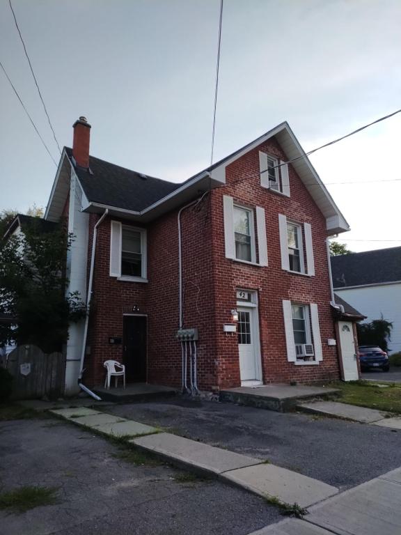 a red brick house with a dog sitting in the driveway at Cozy downtown two bedrooms free parking in Kingston