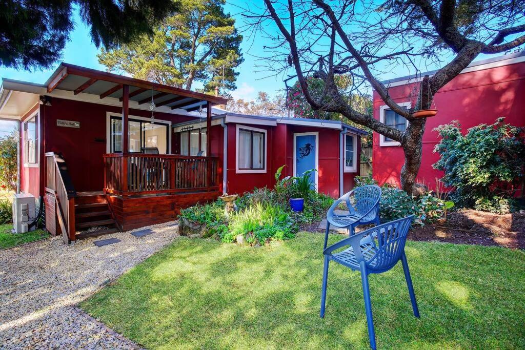 uma casa vermelha com uma cadeira em frente em Tullys Hut em Wentworth Falls