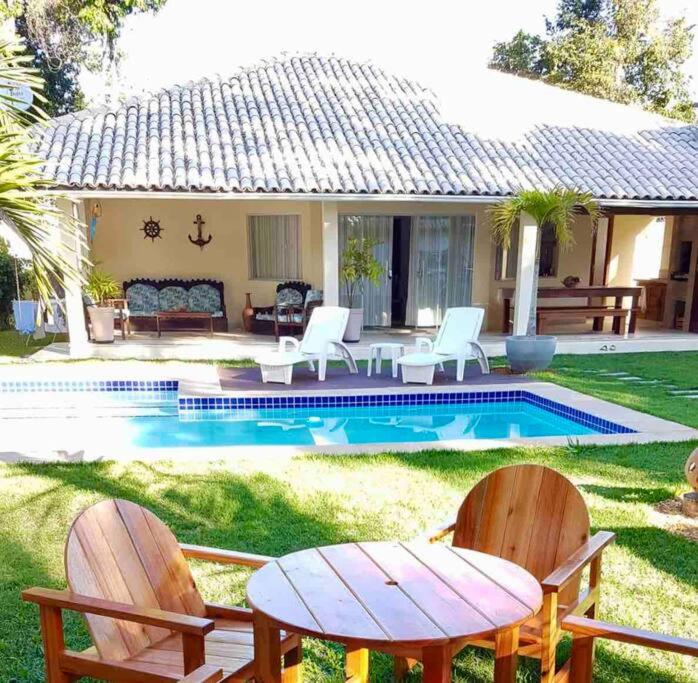 a house with a pool with chairs and a table at Casa Charme Conforto Arraial Dajuda Piscina privativa in Arraial d'Ajuda