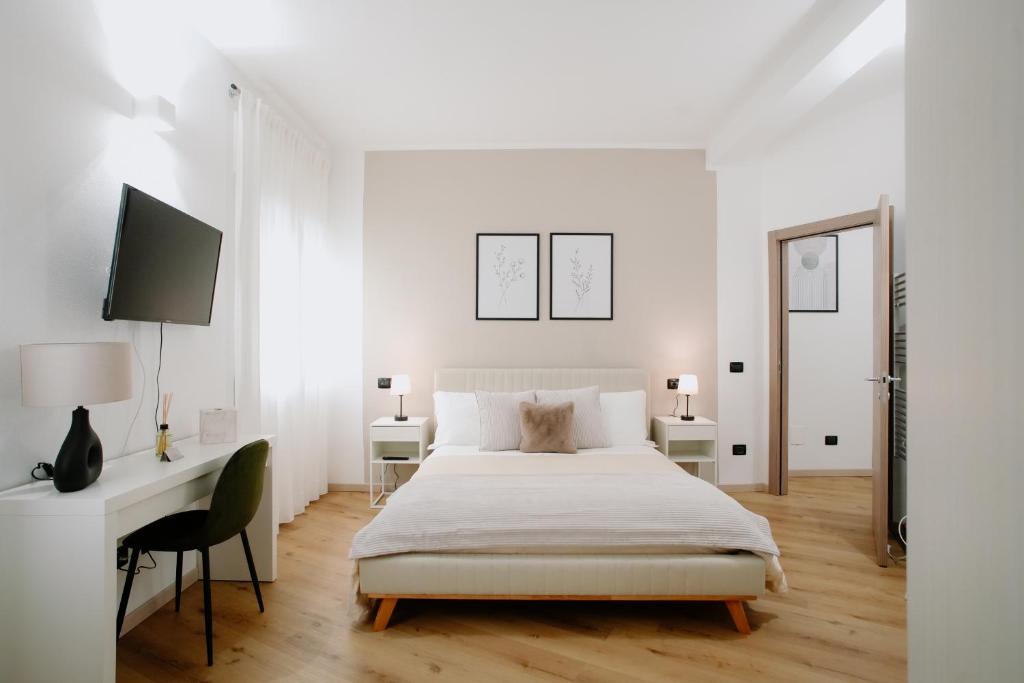 a white bedroom with a bed and a desk at Alatea Apartments Valverde in Verona