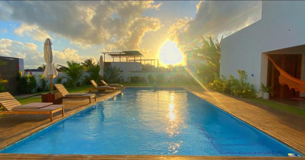 una piscina con sillas y puesta de sol en Villa Paririö, en Canoa Quebrada