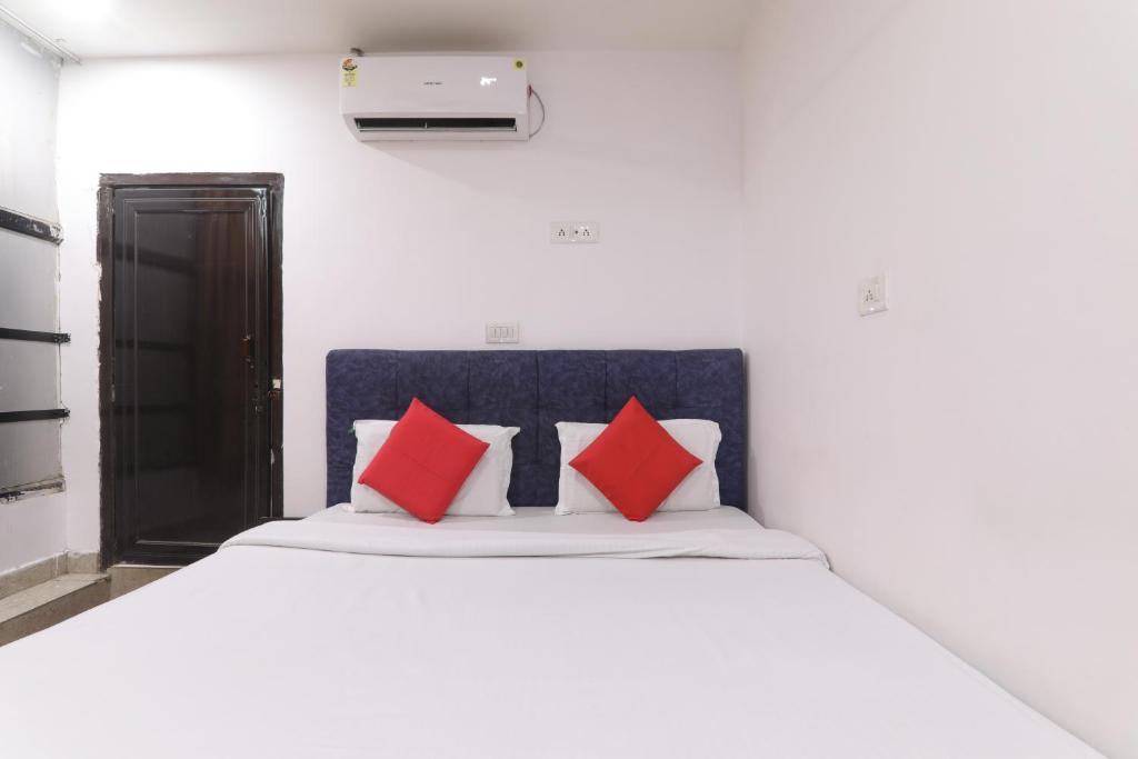 Schlafzimmer mit einem weißen Bett und roten Kissen in der Unterkunft Hotel Metro Regency in Lucknow