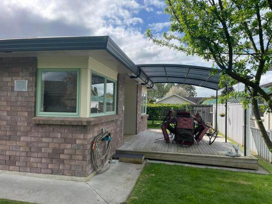 eine Person, die auf einer Veranda eines Hauses sitzt in der Unterkunft POHUTUKAWA PLACE in Matamata