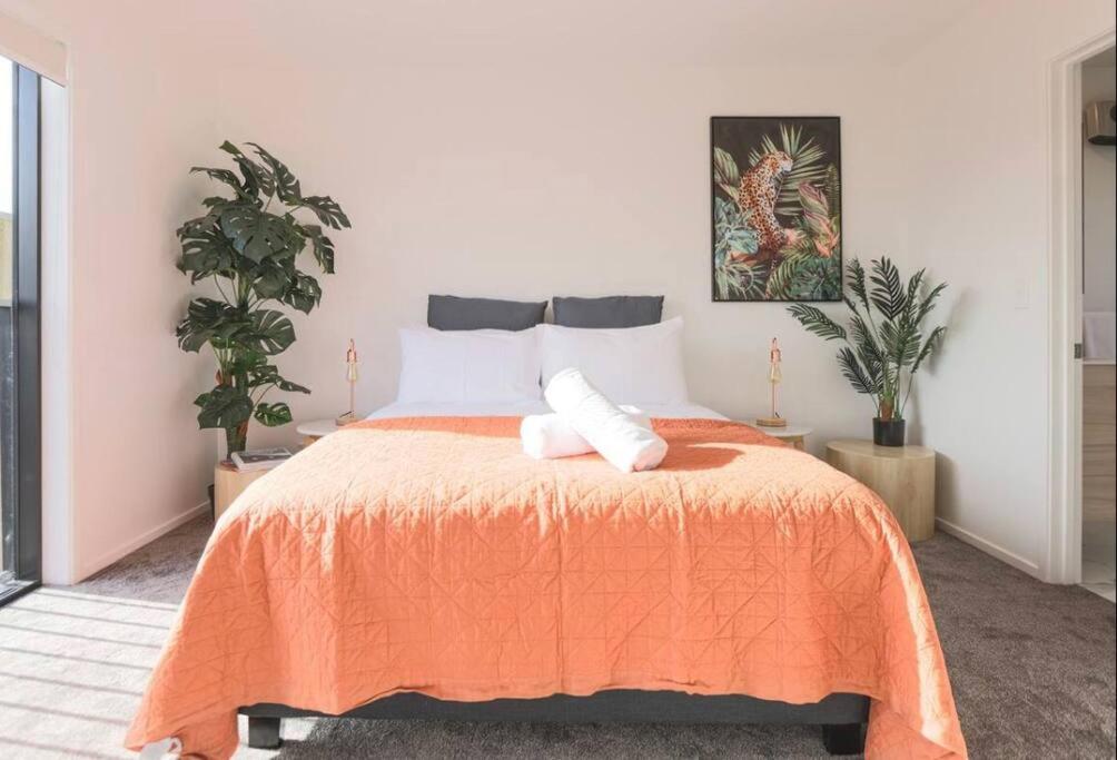 a bedroom with a bed with an orange blanket at CBD with Style and Luxury - Free Parking in Christchurch