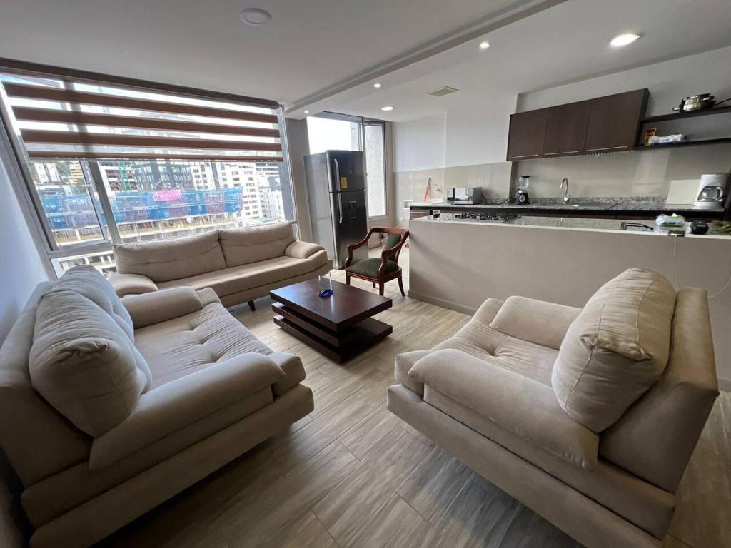 a living room with two couches and a kitchen at Apartamento Sector la Carolina in Quito