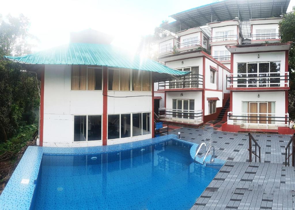 ein Hotel mit einem Pool vor einem Gebäude in der Unterkunft Green Trees Munnar in Munnar