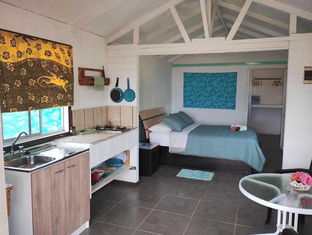 a bedroom with a bed and a kitchen with a sink at Cabañas Kitai in Hanga Roa