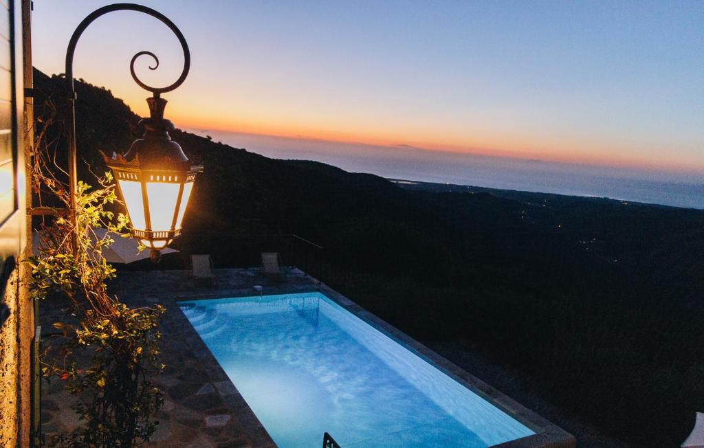 een uitzicht op een zwembad met een lamp en de zonsondergang bij A Macina in Porri