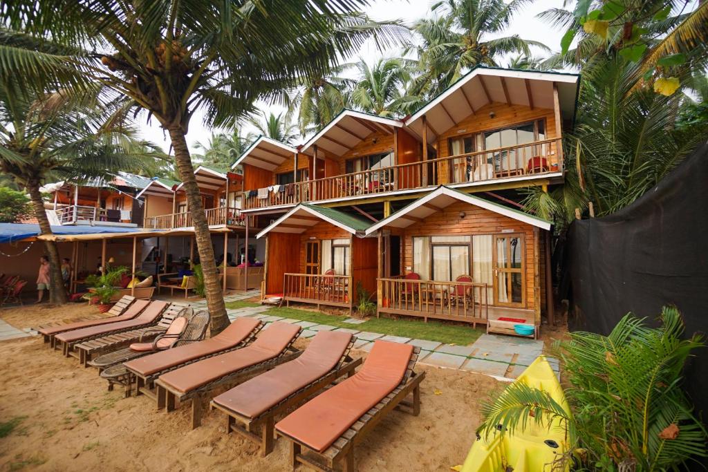 a house on the beach with lounge chairs and palm trees at Sonho do Mar in Agonda