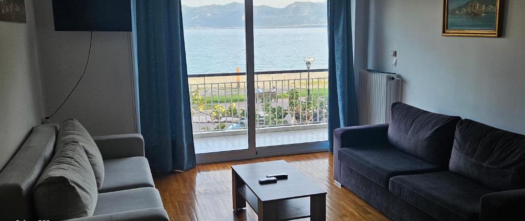 a living room with a couch and a large window at Nafpaktos Beach House in Nafpaktos