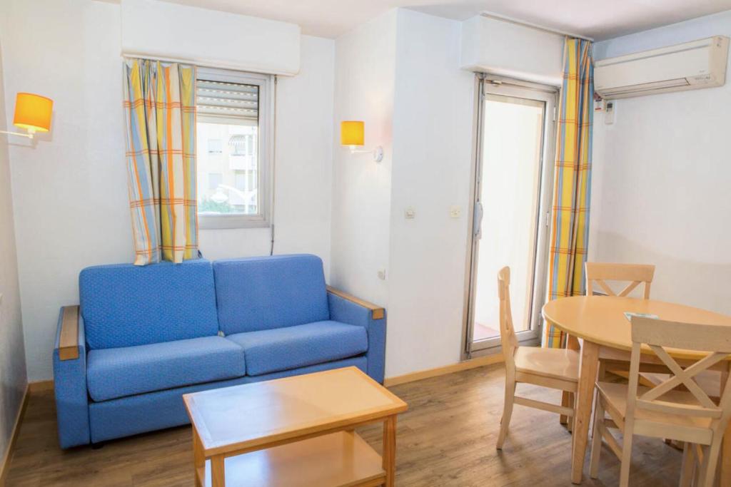 un salon avec un canapé bleu et une table dans l'établissement Résidence Promenade des Bains - maeva Home - Studio 4 Personnes - Confort MAE-2294, à Saint-Raphaël