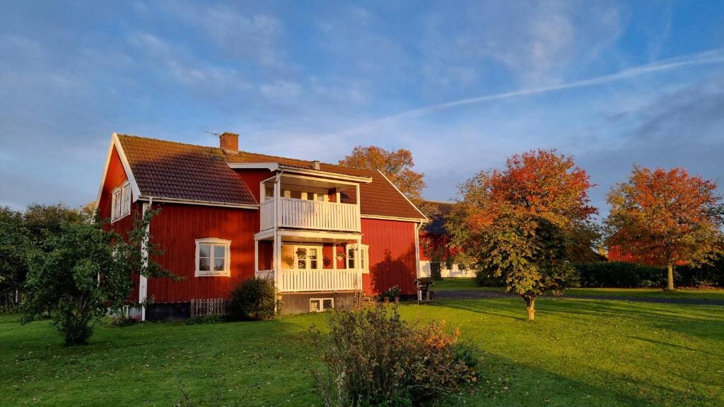 a large red house with a balcony on a yard at Lantligt hus på Knohult in Aneby