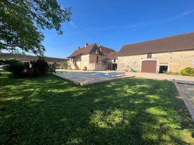 a yard with a house and a large yard with a driveway at Maison de campagne chez Mamie 4 étoiles in Sainte-Eulalie-dʼAns