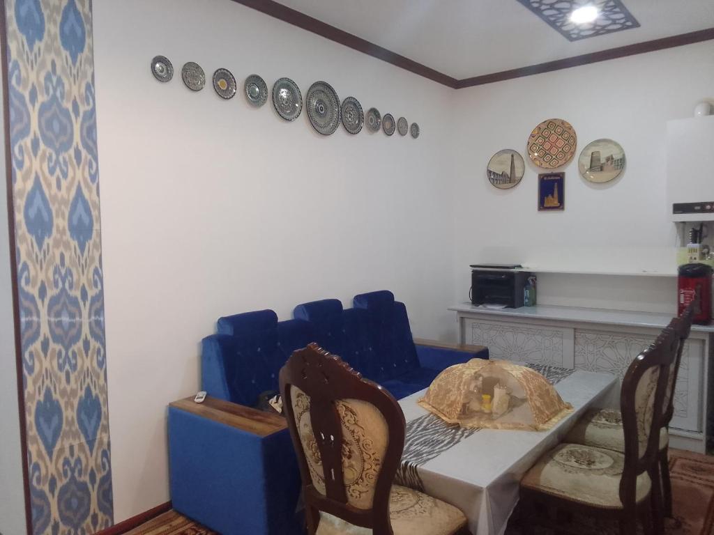 une salle à manger avec une table, des chaises et des assiettes murales dans l'établissement Gavhar House, à Khiva