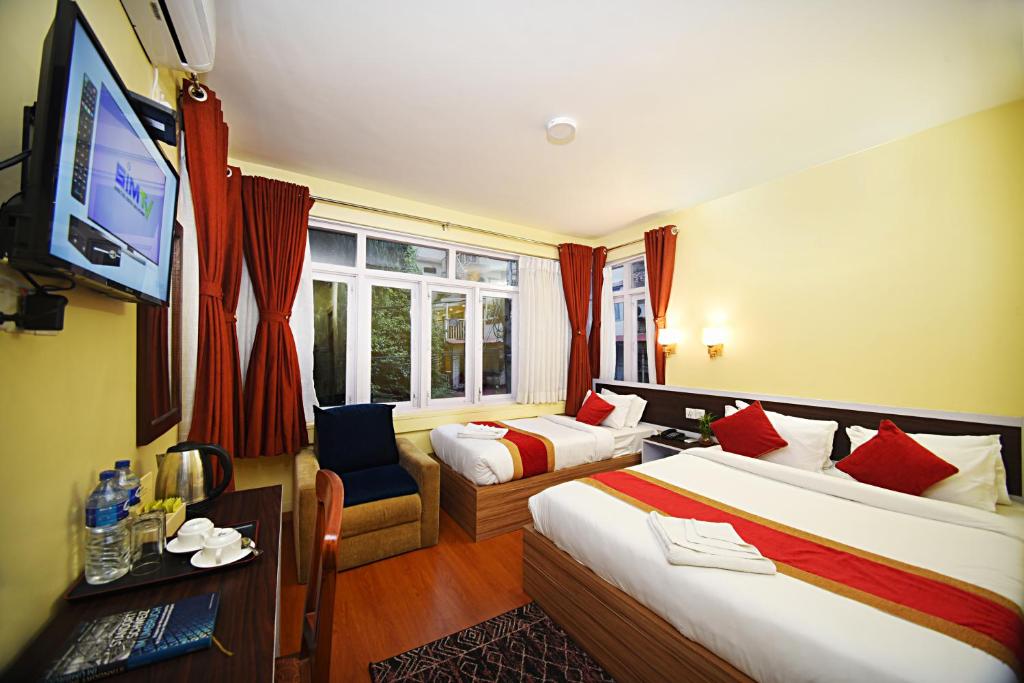 Habitación de hotel con 2 camas y TV de pantalla plana. en Hotel Odyssey Nepal, en Katmandú
