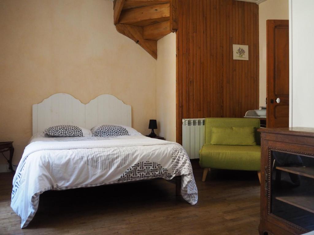 1 dormitorio con 1 cama y 1 silla verde en Maison de La LAFONE, en Domme