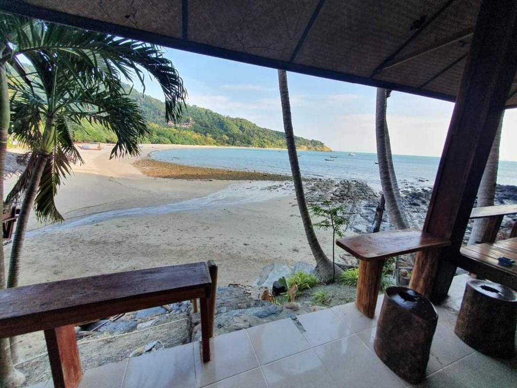 uma vista para a praia a partir de um alpendre com um banco em Family House em Ko Por