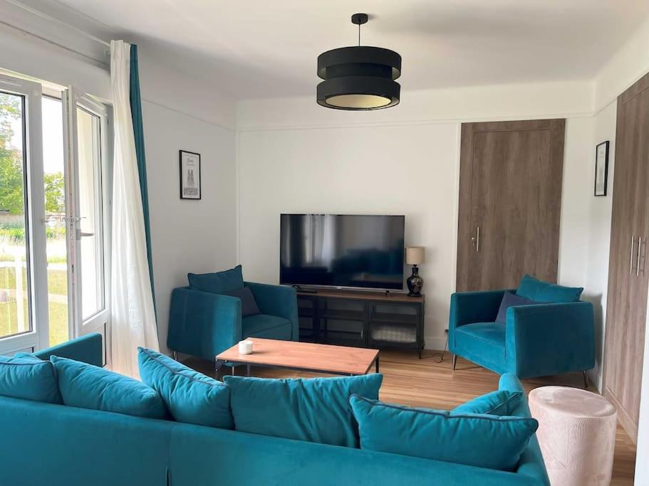 a living room with blue couches and a tv at GÎTES Maisons de Champagnes in Reims