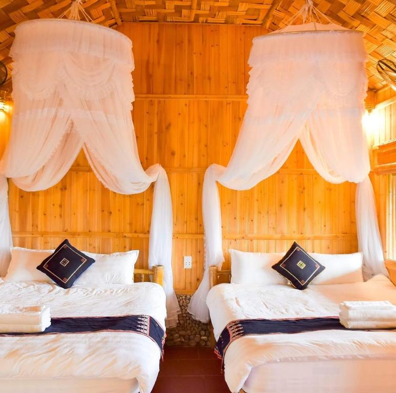 2 Betten in einem Zimmer mit Vorhängen darüber in der Unterkunft Dao Homestay in Hoàng Su Phì