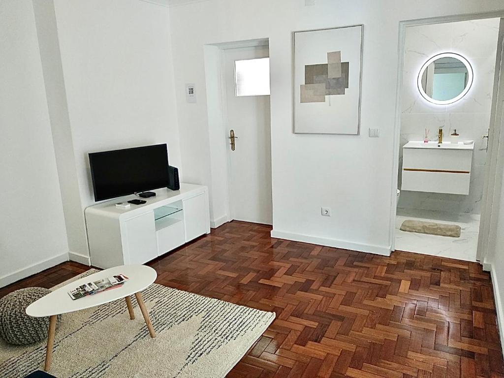 ein Wohnzimmer mit einem TV und einem Tisch in der Unterkunft Cantinho do Castelo in Bragança
