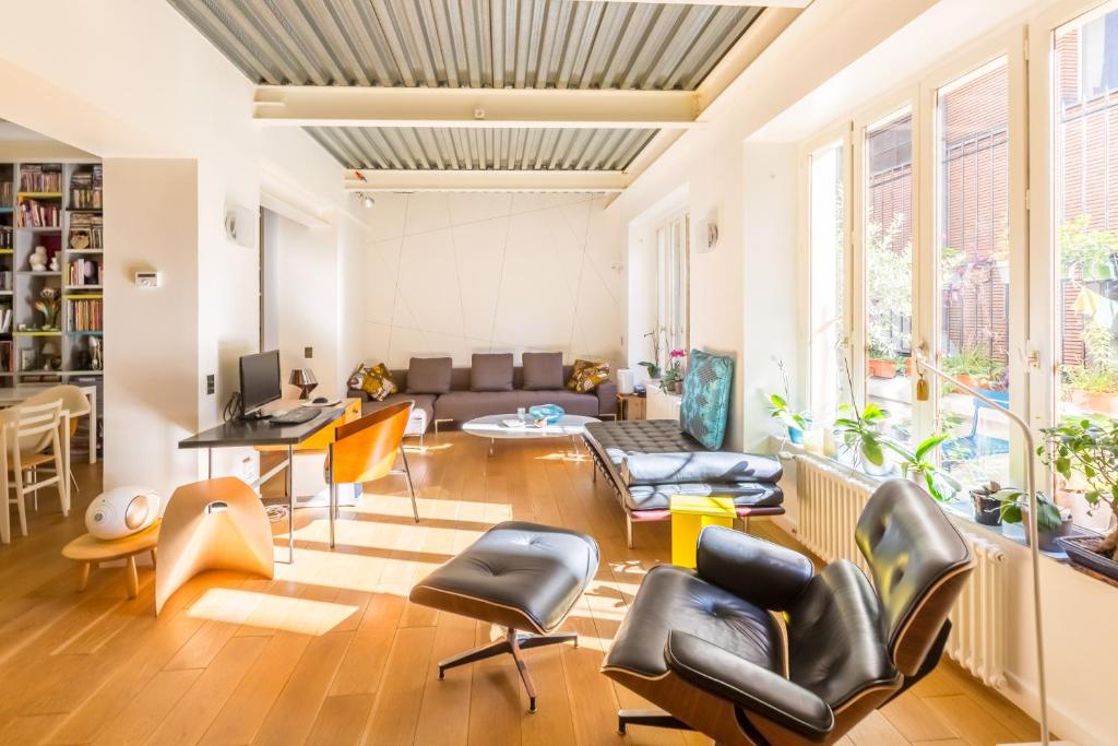 ein Wohnzimmer mit einem Sofa und Stühlen in der Unterkunft LOFT 11e près Canal St-Martin - Chambre climatisée SDB privée in Paris