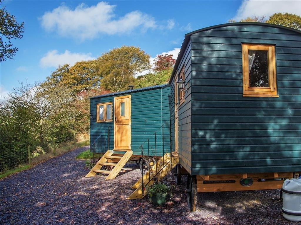 a green tiny house sitting on a gravel lot at Siabod Huts in Betws-y-coed