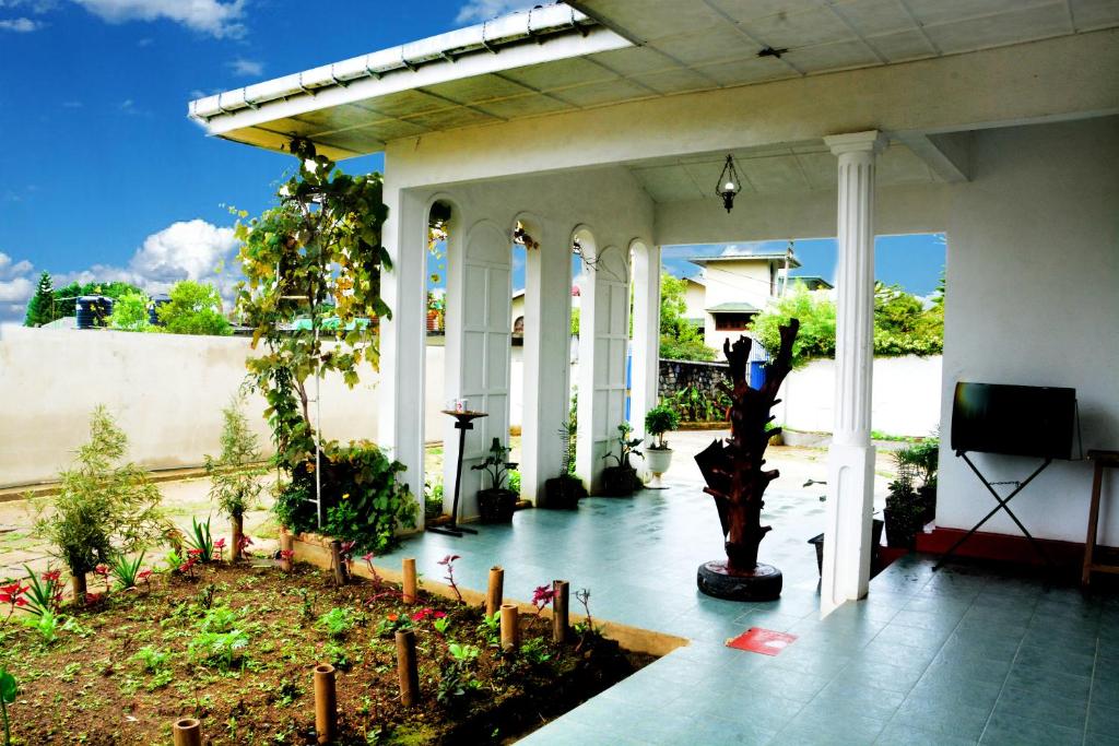 una casa con un patio con un árbol. en The West Gate Bungalow en Nuwara Eliya