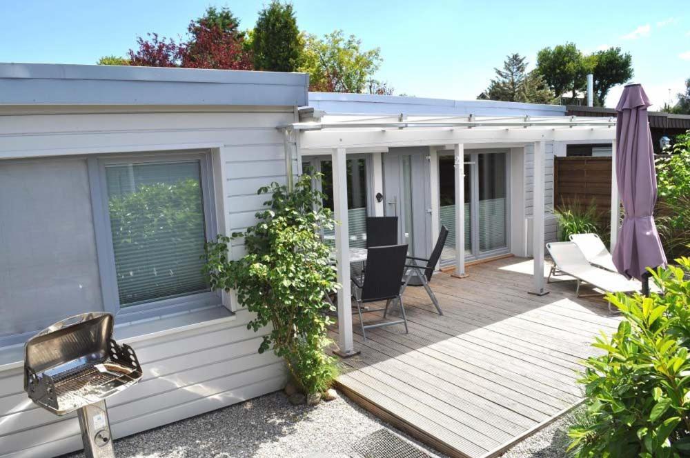 uma casa com um deque com uma mesa e cadeiras em Haus Chalet 21 Ferienhaus em Haffkrug