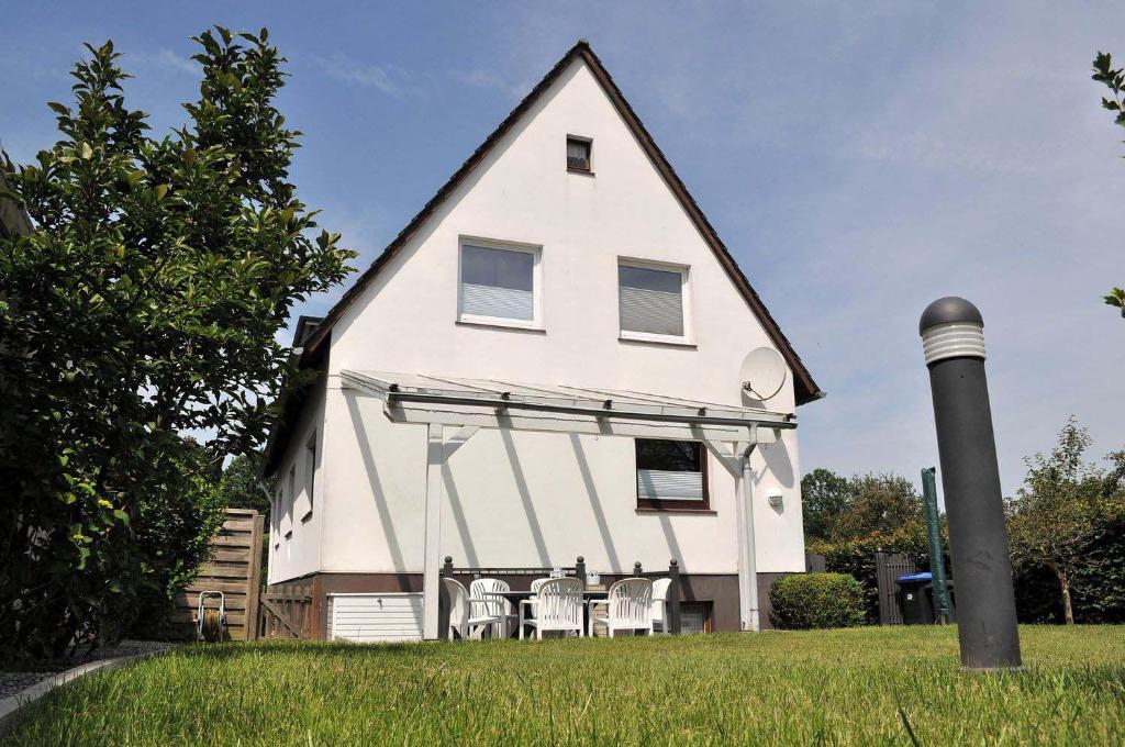 une grande maison blanche avec des chaises en face de celle-ci dans l'établissement Haus Seehase Ferienwohnung Nr 03, à Haffkrug