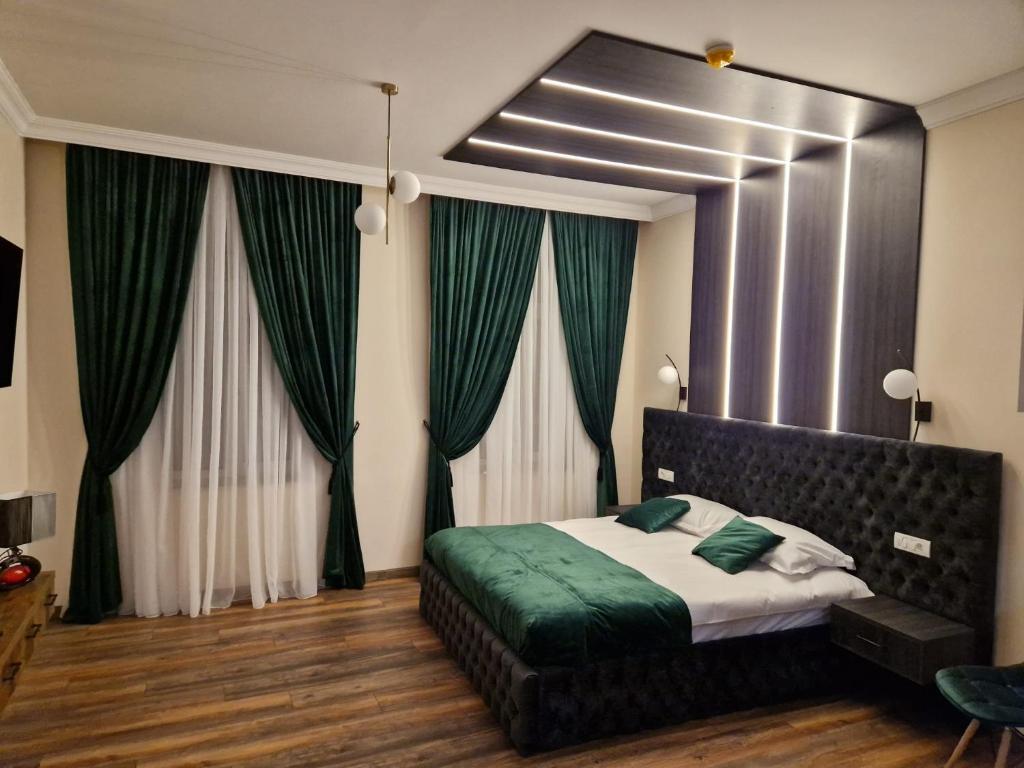 a bedroom with a bed with green sheets and curtains at Bizi House Accommodation in Drobeta-Turnu Severin