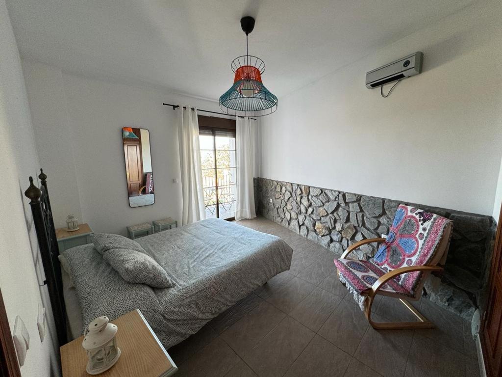 um quarto com uma cama, uma cadeira e uma janela em apartamento arroyo em Benaocaz