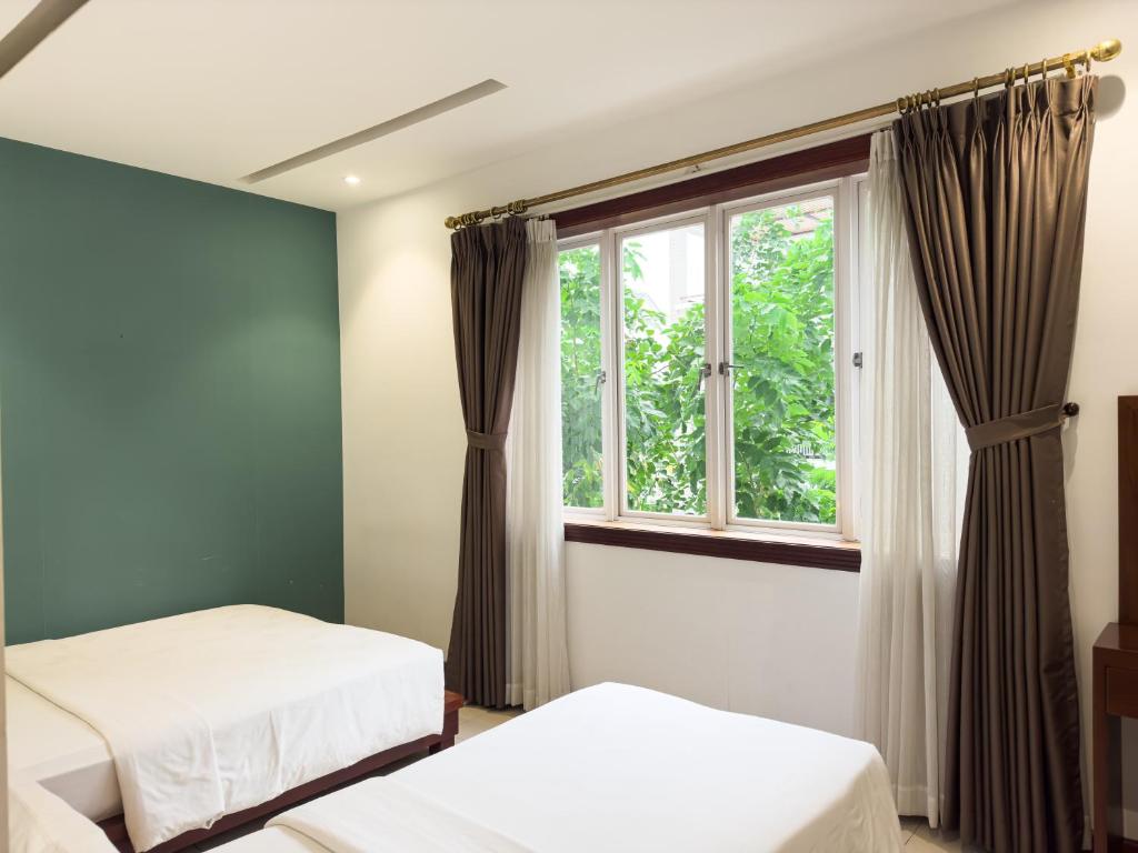 a bedroom with two beds and a window at Hoang Yen Hotel - Phu My Hung in Ho Chi Minh City