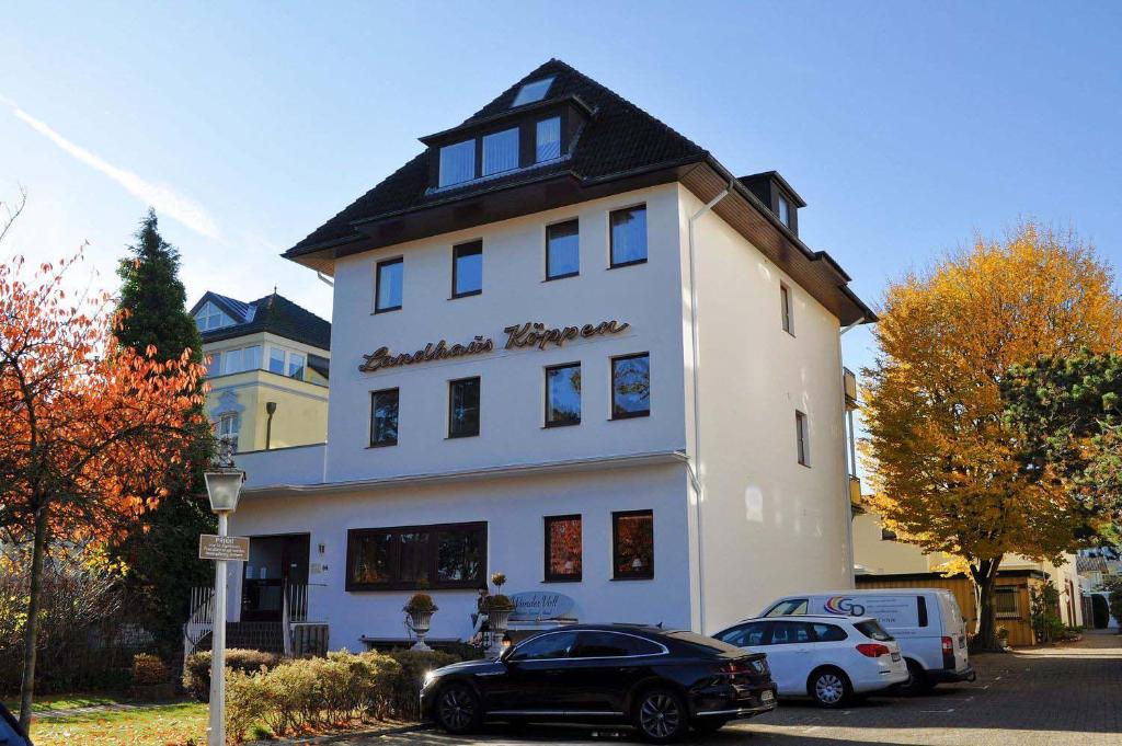 蒂門多爾費爾斯特蘭德的住宿－Landhaus Köppen Ferienwohnung Nr 15，一座白色的建筑,前面有汽车停放