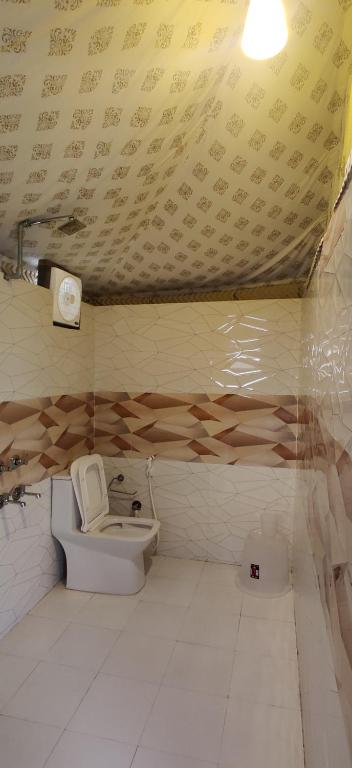 a bathroom with a toilet and a ceiling with writing at Beaumont Glamping Eco Resort in Dharamshala