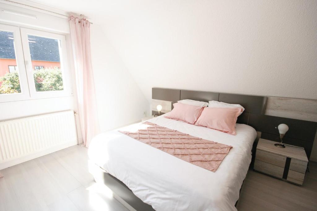 - une chambre avec un lit doté d'oreillers roses et d'une fenêtre dans l'établissement Gîte La Maison de Ludivine avec Terrasse et Parking, à Orbey