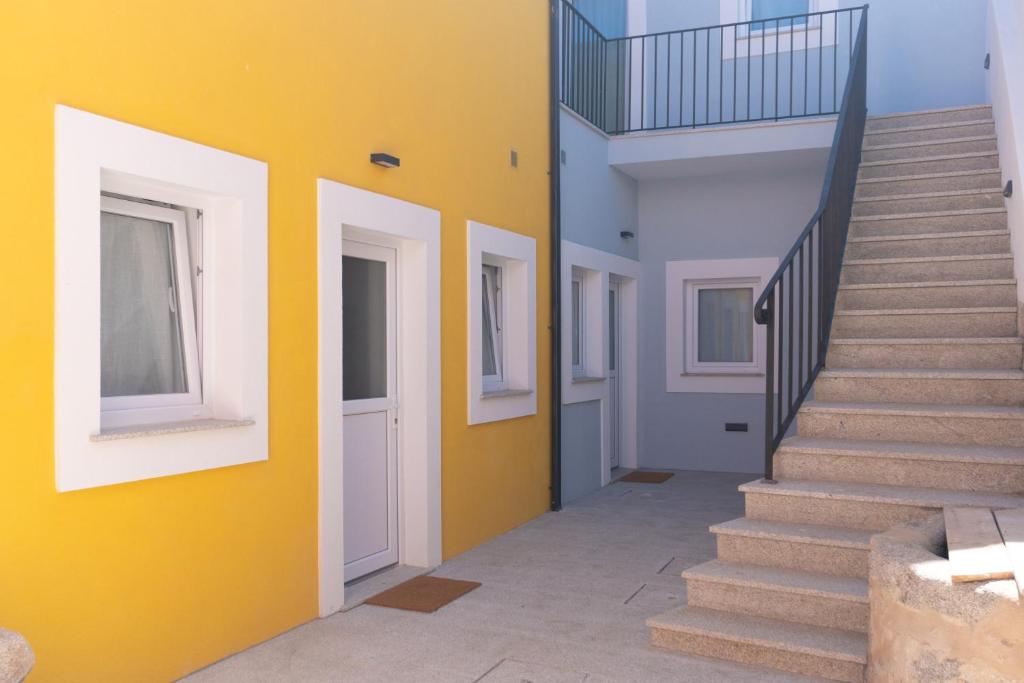 a hallway with stairs and a yellow wall at Canary's Suite in Matosinhos