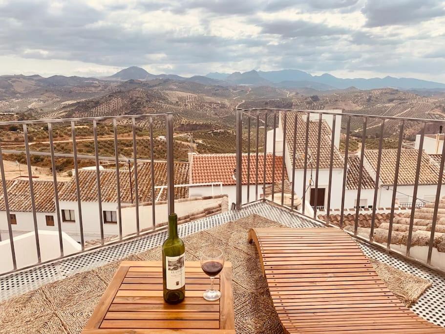 Una botella de vino sentada en una mesa de madera en un balcón en NO. 32 with stunning views, en Olvera