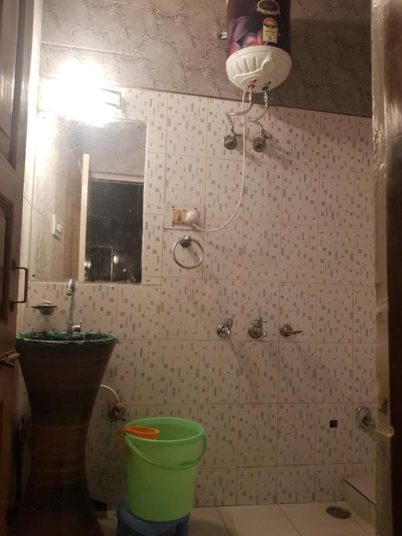 a bathroom with a shower and a green bucket at Chauhan Homestay in Shimla