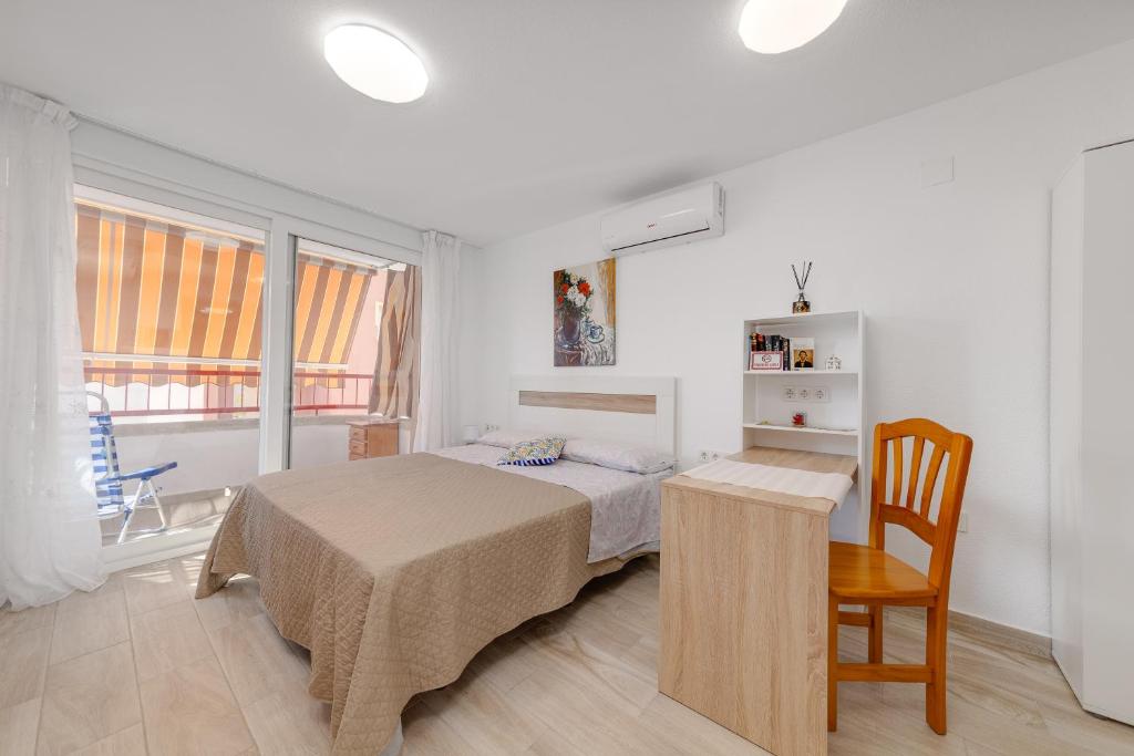 ein Schlafzimmer mit einem Bett, einem Tisch und einem Stuhl in der Unterkunft Cosy Studio Playa del Cura in Torrevieja