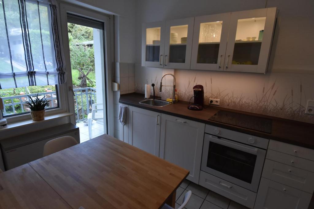 a kitchen with white cabinets and a wooden counter top at Ferienwohnung Hohenlimburg in Hagen