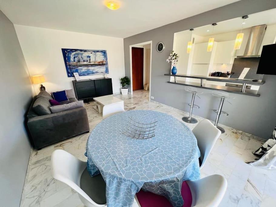 a living room with a blue table and white chairs at Le Pinède - Apt 4 Prs- Parking - Clim - 500m plages in Antibes