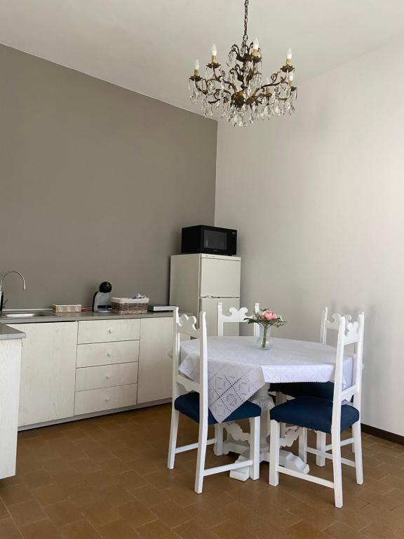 a kitchen with a white table and chairs and a chandelier at B&B Le Rose in Villafranca Padovana