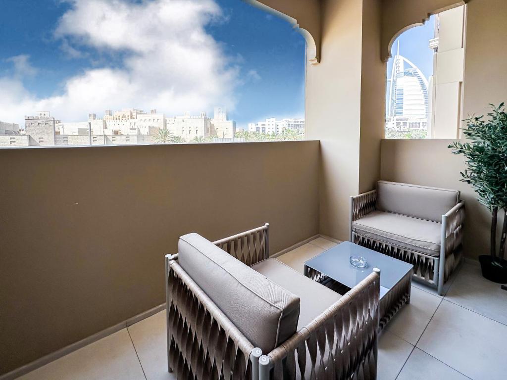 Trophy Luxe Jumeirah Retreat w Burj Al ARB views في دبي: بلكونه فيها كراسي وطاولة ونافذة