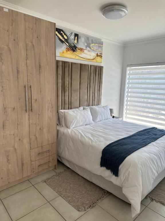 1 dormitorio con 1 cama grande y armarios de madera en Maadima, The Yard, en Edenvale