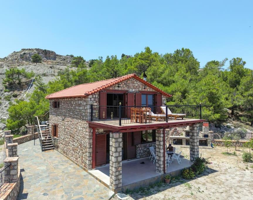 a small stone house with a balcony and a deck at Petronas Land House 2 in Archangelos