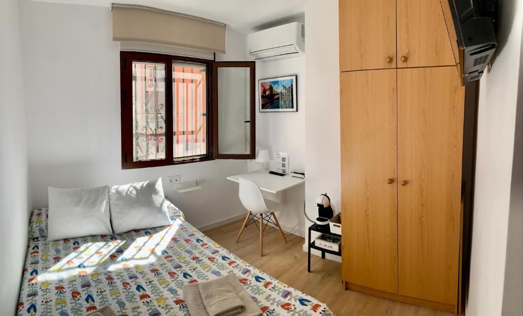 a small bedroom with a bed and a desk at Habitación González in Málaga