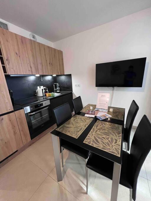 - une cuisine avec une table, des chaises et une cuisinière dans l'établissement Le Cosy Corner : Apt 2 pers de standing + Terrasse, à Antibes