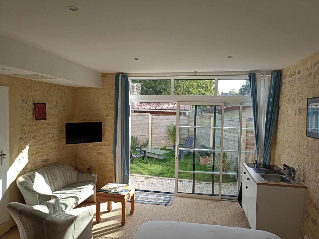 un salon avec un canapé et une cuisine avec une fenêtre dans l'établissement Studio Vargas avec jardin - Omaha Beach, à Colleville-sur-Mer
