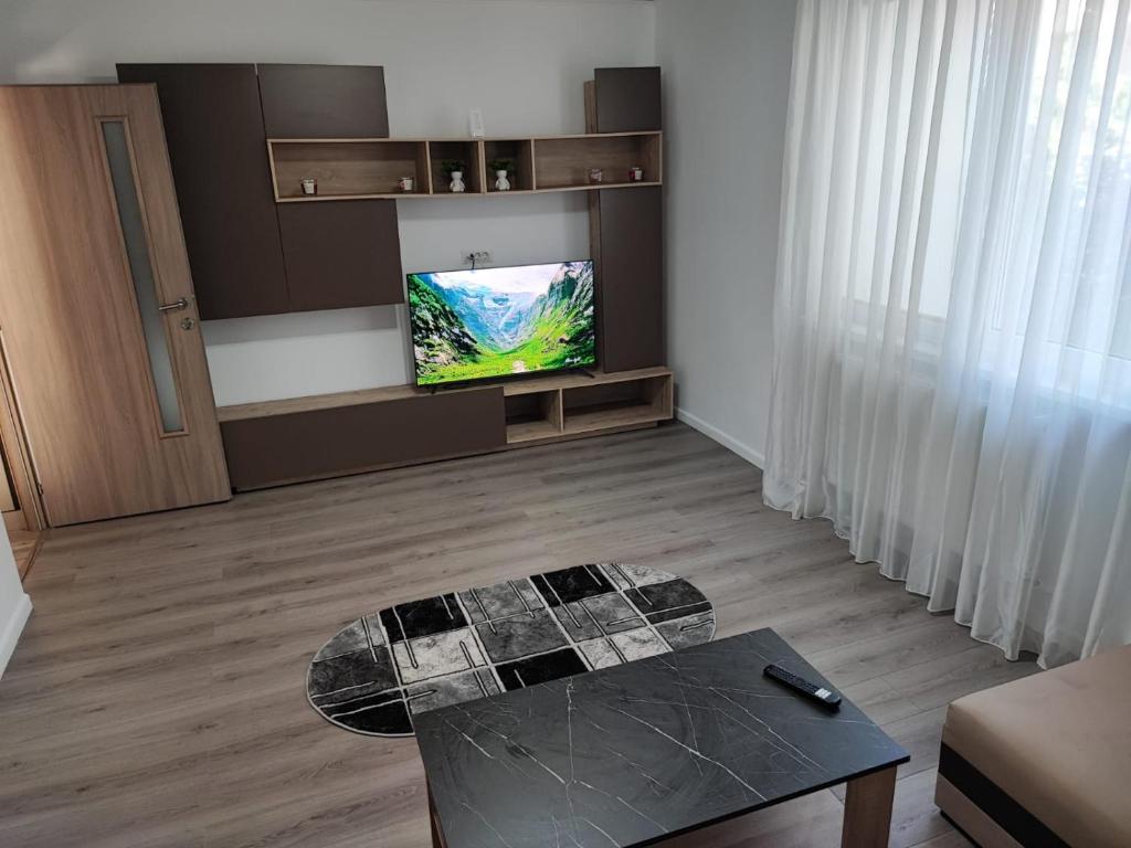 a living room with a table and a flat screen tv at A&A Residence in Piatra Neamţ