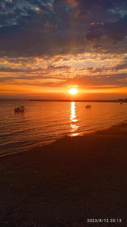 a sunset on the beach with boats in the water at Roses Apartments in Nea Michaniona